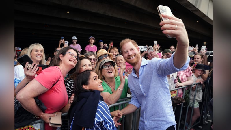 FILE -- Prince Harry and Meghan, the Duke and Duchess of Sussex, pose for a selfie photo with...