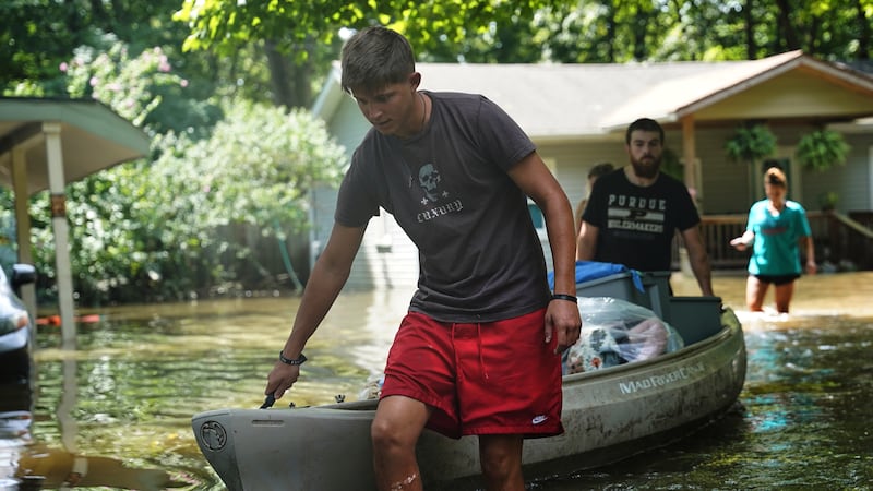 Residents transport items from their flooded homes by kayak in Indianapolis, Sunday, Aug. 16,...