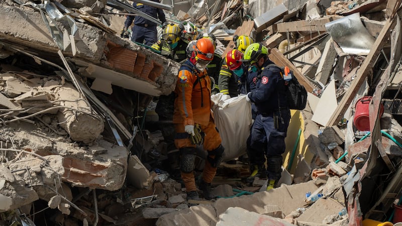 Rescuers carry the body of a victim from the rubble four days after after an earthquake hit...