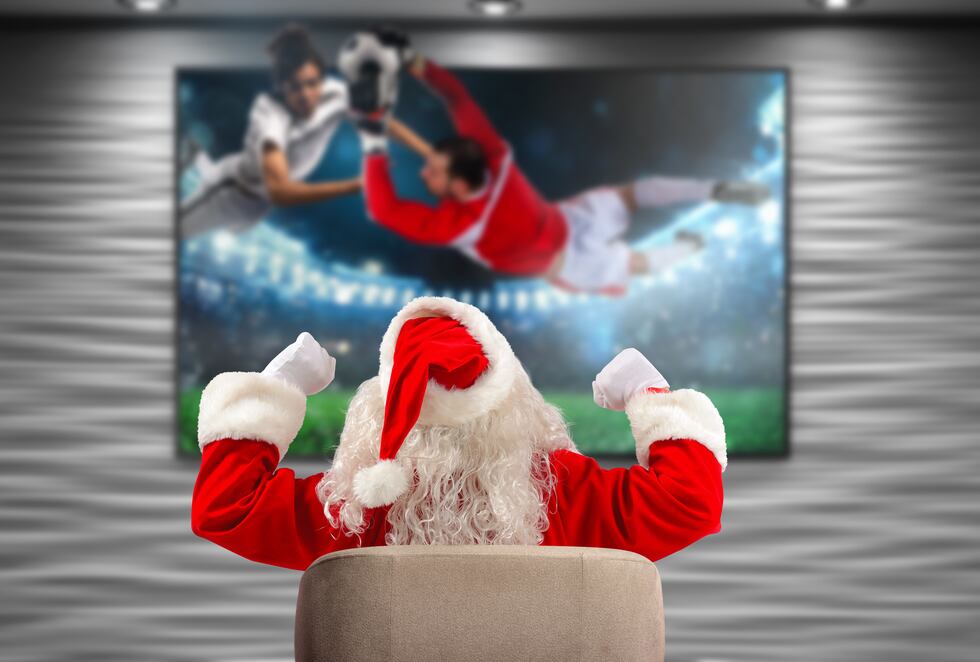Santa Claus watching a soccer match on tv